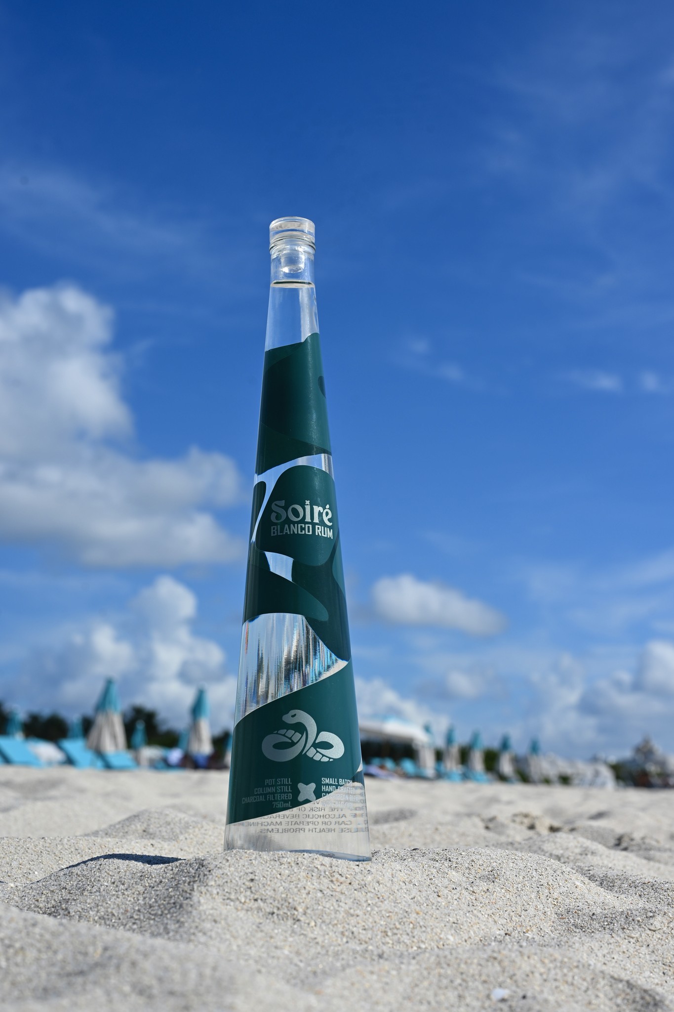 SOIRÉ Blanco bottle standing in sand against a blue sky