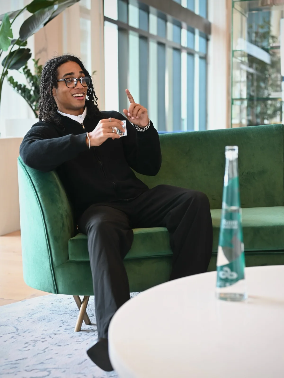 Kash Corleone Rogers seated indoors with a SOIRÉ bottle in the foreground